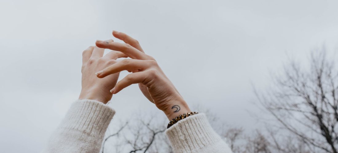 hands toward sky moon wrist tattoo