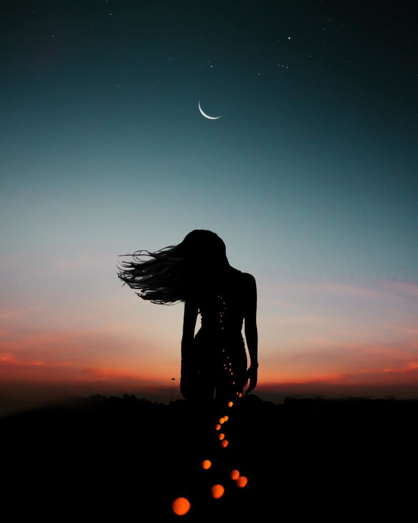 woman under moon phase with bokeh coming out