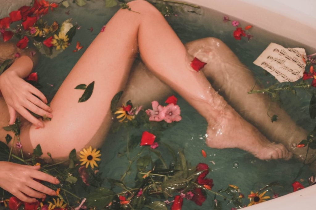 female in bath with flowers in a self-care moment 